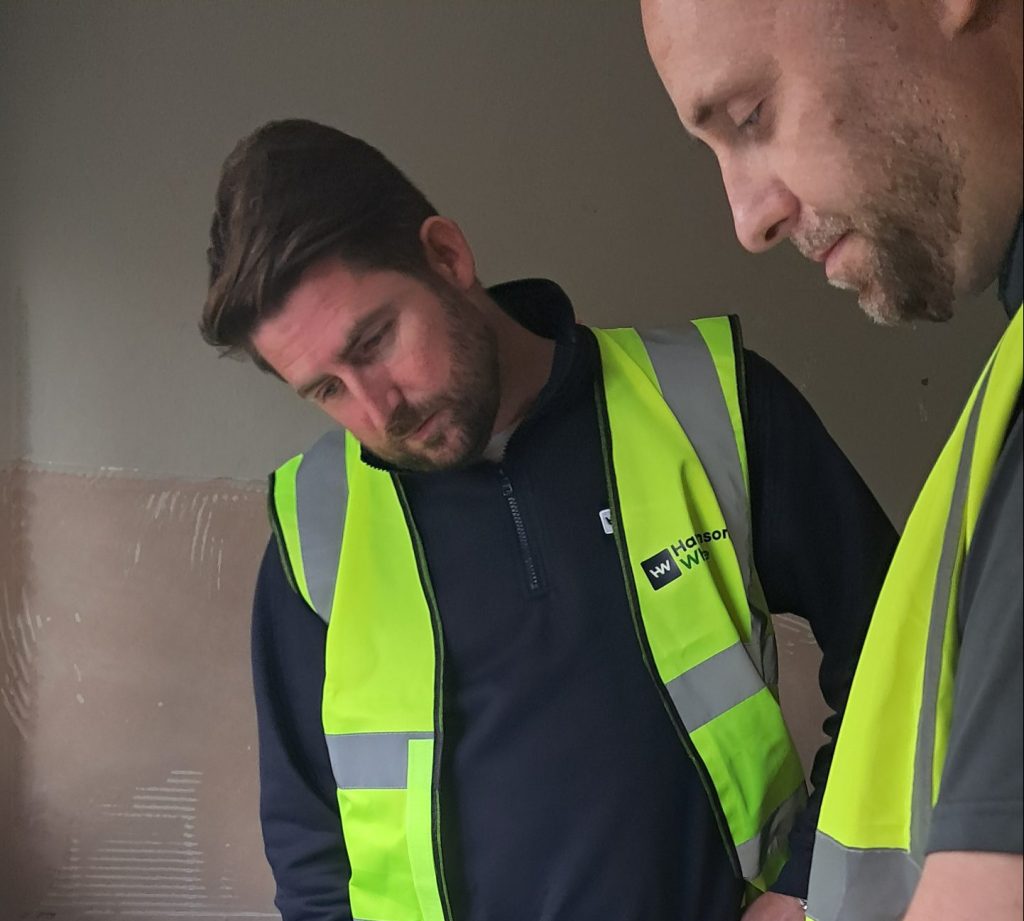 Two mean in hi-viz vests looking at housing plans