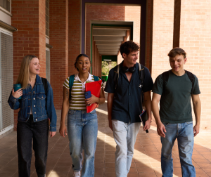 A group of college students walking through an outside walkway of a red brick education building
