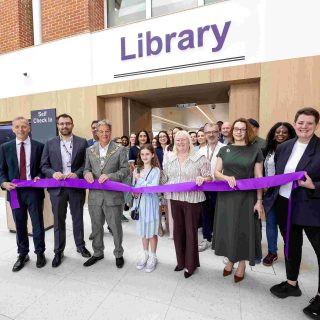 Reading's Mayor along with other public officials and library staff stand outside the new Reading Central Library with a purple ribbon which is about to be cut.